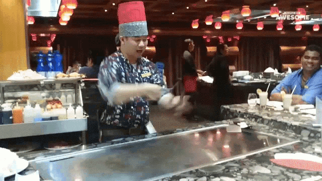 Chef tossing knives around a hibachi grill